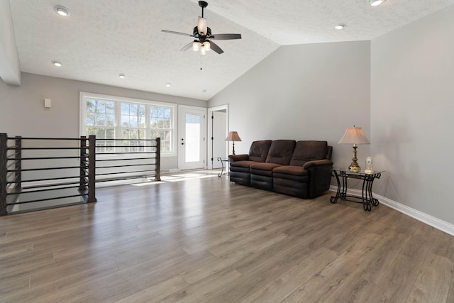 living area featuring a textured ceiling, wood finished floors, a ceiling fan, and vaulted ceiling