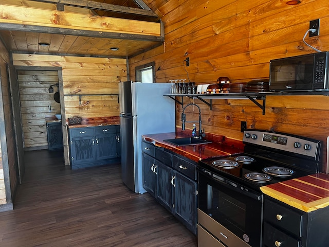 kitchen with sink, wooden walls, lofted ceiling, dark hardwood / wood-style floors, and appliances with stainless steel finishes