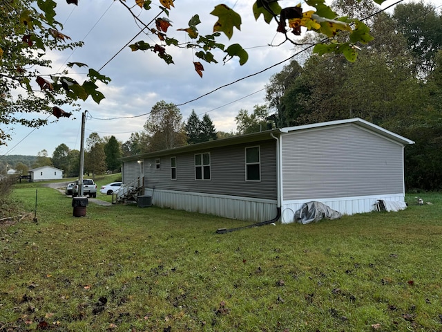 view of side of property with central air condition unit and a lawn