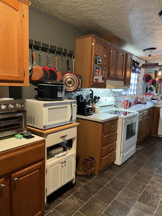 kitchen featuring white appliances, tasteful backsplash, and a textured ceiling