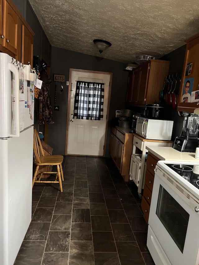 kitchen with white appliances, brown cabinets, and a textured ceiling