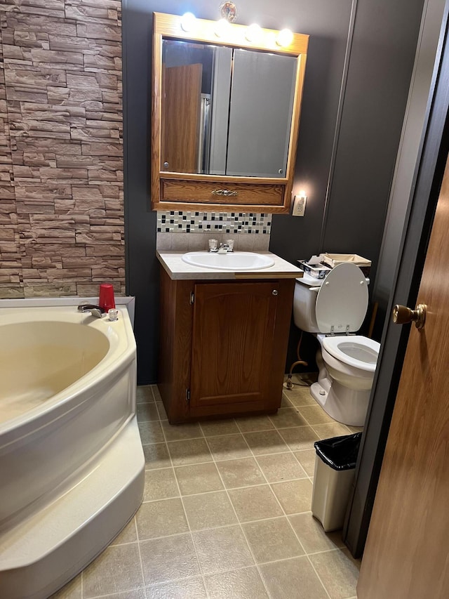 full bathroom featuring tile patterned floors, toilet, decorative backsplash, vanity, and a bath