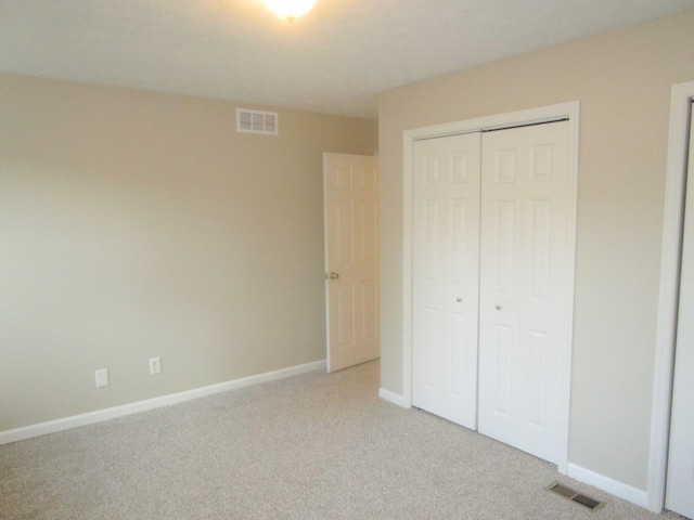 unfurnished bedroom with light colored carpet and a closet