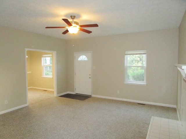 interior space with ceiling fan, a wealth of natural light, and light colored carpet