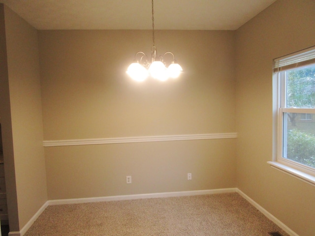 carpeted spare room with an inviting chandelier