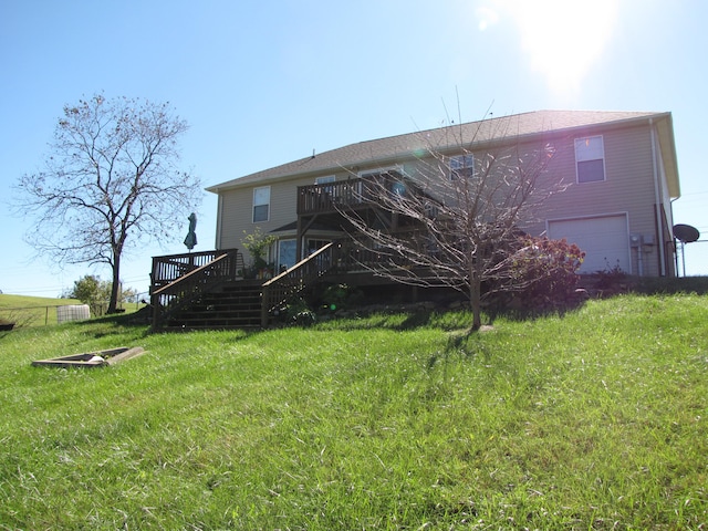 rear view of property featuring a garage, a wooden deck, and a yard