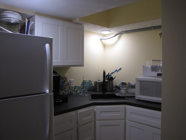 kitchen featuring a textured ceiling, white appliances, and white cabinetry