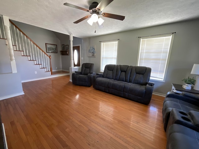 living room featuring light wood-type flooring, ceiling fan, and a textured ceiling