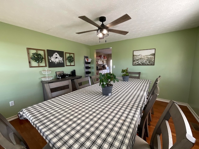 dining area with ceiling fan, wood-type flooring, and a textured ceiling