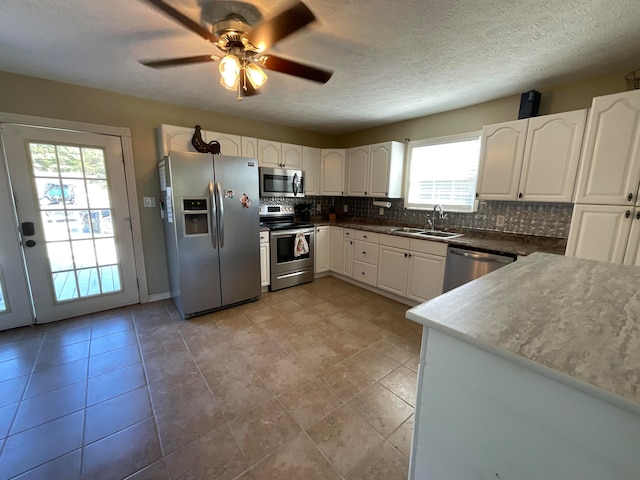 kitchen with tasteful backsplash, appliances with stainless steel finishes, sink, and white cabinetry