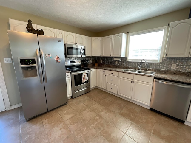 kitchen featuring tasteful backsplash, white cabinets, appliances with stainless steel finishes, and sink