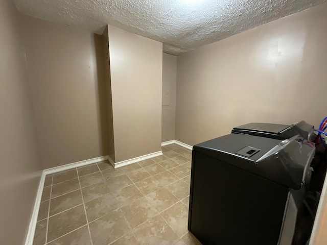 washroom featuring independent washer and dryer, light tile patterned floors, and a textured ceiling