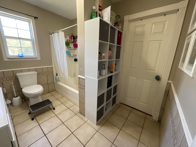 bathroom featuring shower / bath combo, tile patterned floors, toilet, and tile walls