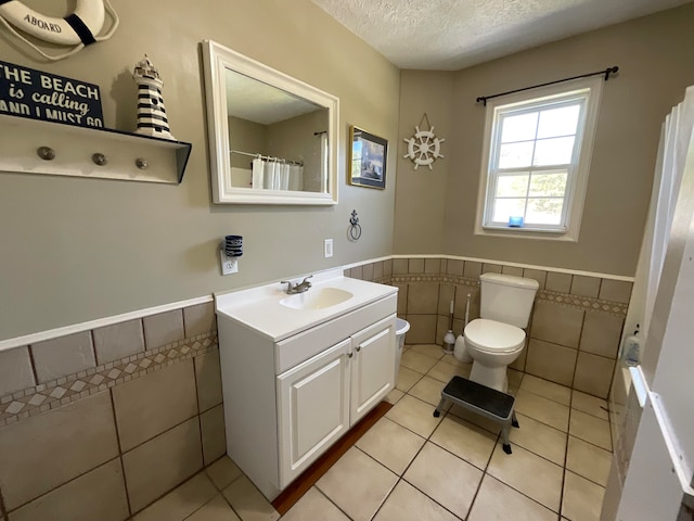 bathroom with tile patterned flooring, vanity, tile walls, and toilet