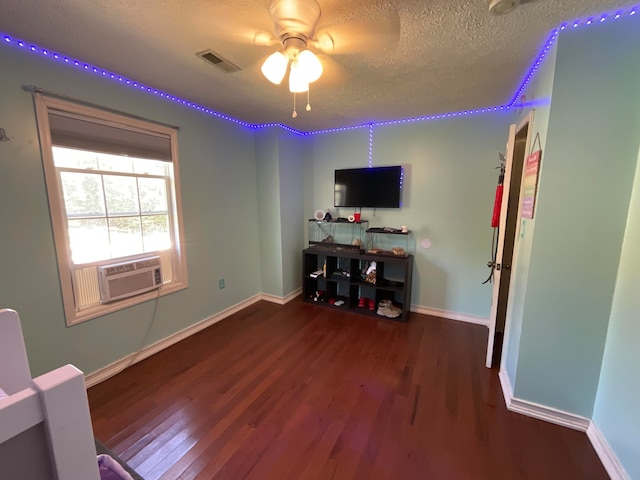 living room featuring cooling unit, dark hardwood / wood-style floors, a textured ceiling, and ceiling fan