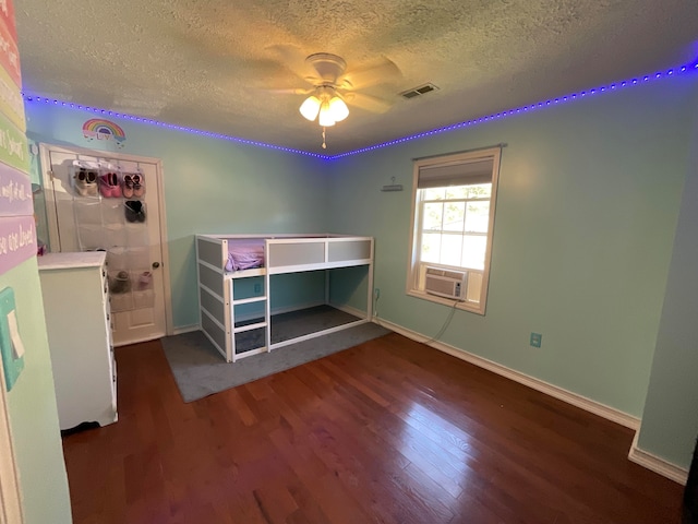 unfurnished bedroom with cooling unit, dark hardwood / wood-style floors, a textured ceiling, and ceiling fan