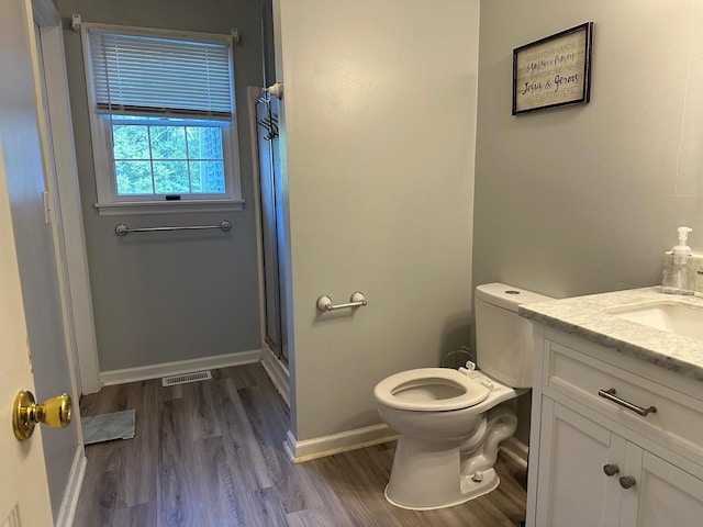 bathroom with walk in shower, hardwood / wood-style floors, vanity, and toilet