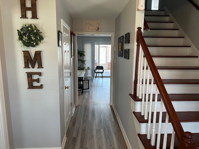 corridor with baseboards, wood finished floors, and stairs