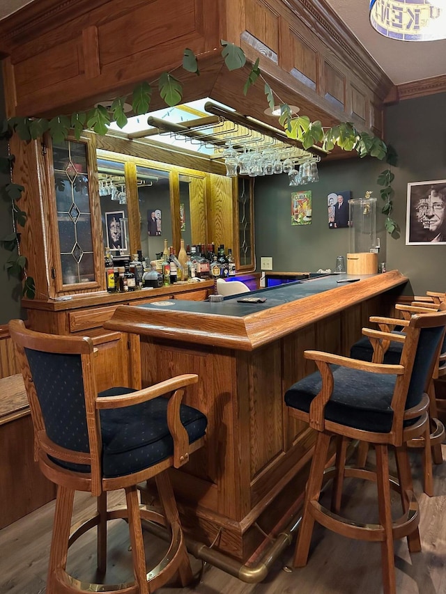 bar with ornamental molding and wood-type flooring