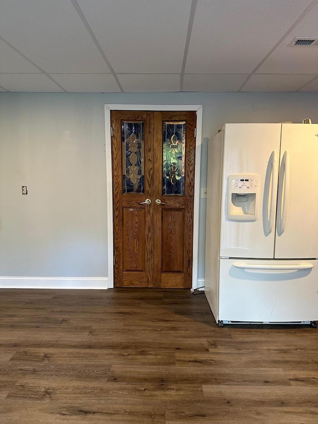 interior space with dark wood-type flooring, a paneled ceiling, and white fridge with ice dispenser