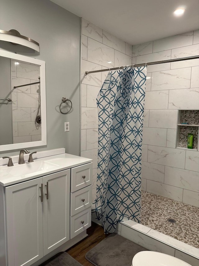 bathroom featuring a shower with shower curtain, hardwood / wood-style flooring, vanity, and toilet