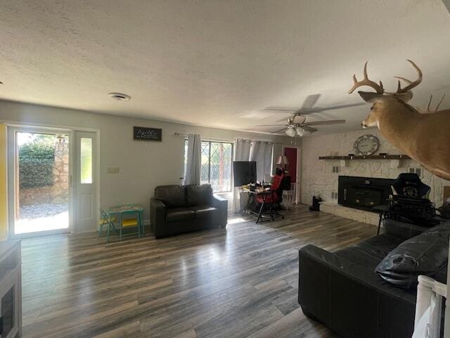 living room with a fireplace, ceiling fan, hardwood / wood-style floors, and a textured ceiling