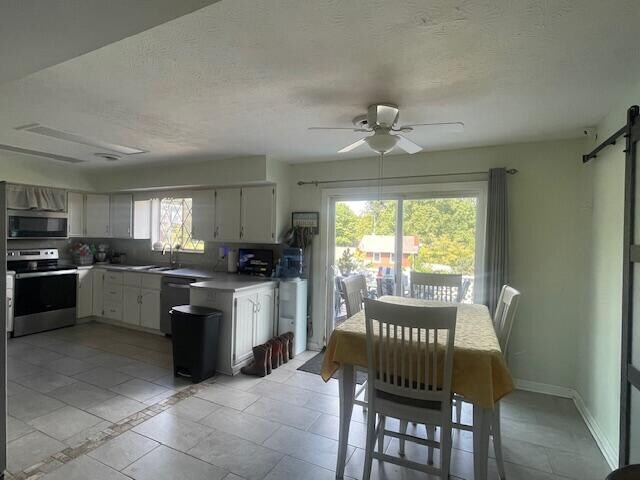 kitchen with ceiling fan, light tile patterned floors, sink, appliances with stainless steel finishes, and a barn door