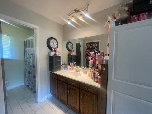 bathroom with vanity, tile patterned flooring, toilet, and curtained shower