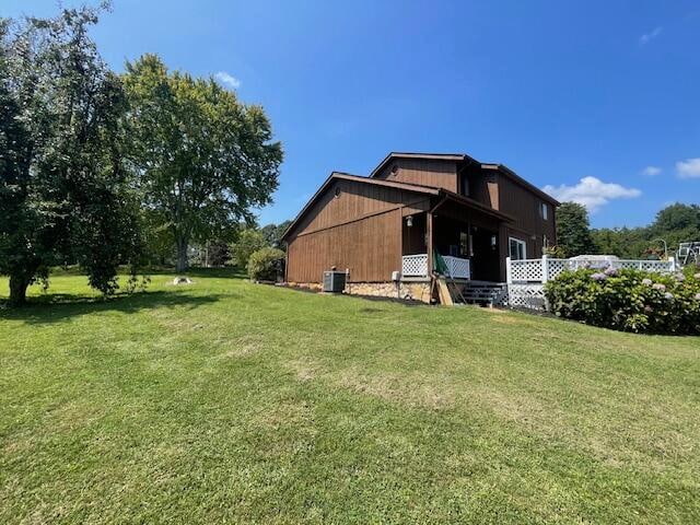 rear view of property featuring a yard and central AC unit