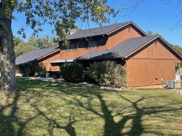 view of property exterior with central AC unit and a yard