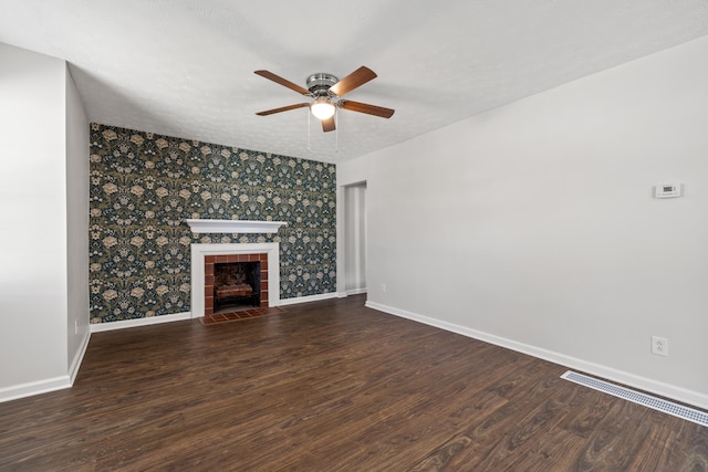 unfurnished living room with a tiled fireplace, dark hardwood / wood-style flooring, a textured ceiling, and ceiling fan