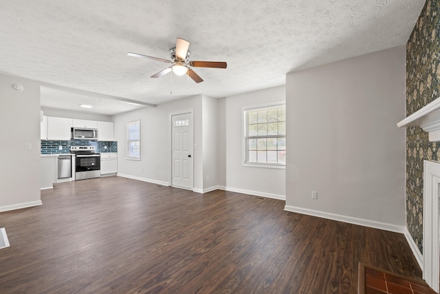 unfurnished living room featuring ceiling fan, a textured ceiling, and dark hardwood / wood-style floors