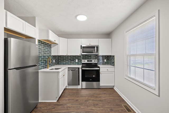 kitchen featuring dark hardwood / wood-style floors, appliances with stainless steel finishes, sink, and white cabinetry