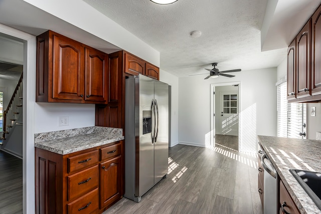 kitchen featuring ceiling fan, hardwood / wood-style floors, stainless steel appliances, and a textured ceiling