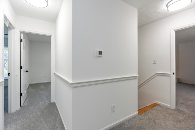 hall with a textured ceiling and carpet flooring