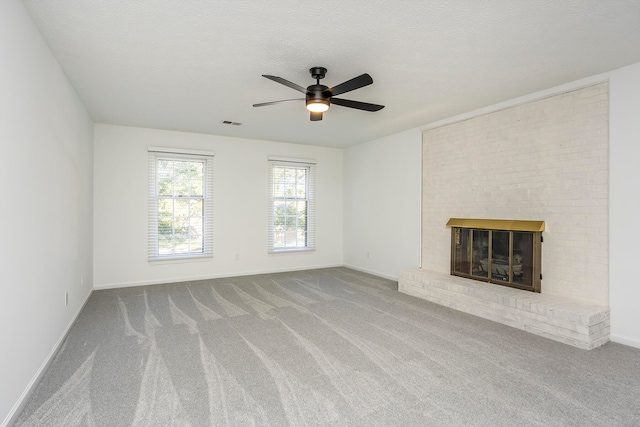 unfurnished living room featuring a brick fireplace, a textured ceiling, carpet flooring, and ceiling fan