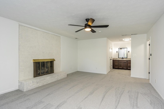 unfurnished living room featuring ceiling fan, a fireplace, a sink, baseboards, and light carpet