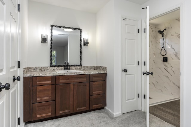 full bathroom with vanity, a marble finish shower, and baseboards