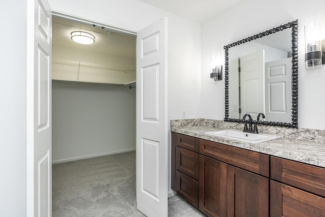 bathroom featuring vanity, baseboards, and a spacious closet