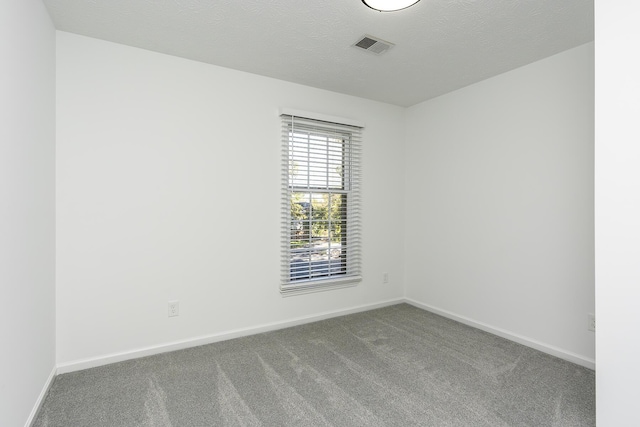 carpeted empty room featuring baseboards, a textured ceiling, and visible vents
