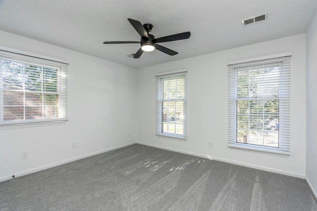 empty room with dark carpet, a wealth of natural light, and ceiling fan