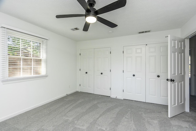 unfurnished bedroom with visible vents, carpet, multiple closets, and baseboards