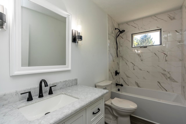 full bathroom with tiled shower / bath, vanity, toilet, and a textured ceiling