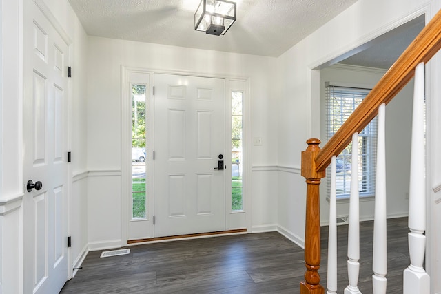 foyer featuring a textured ceiling, crown molding, and dark hardwood / wood-style flooring