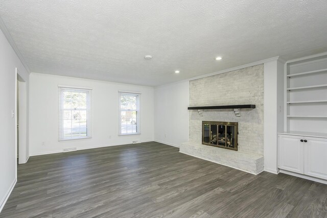 unfurnished living room featuring ornamental molding, a brick fireplace, a textured ceiling, and dark wood-type flooring