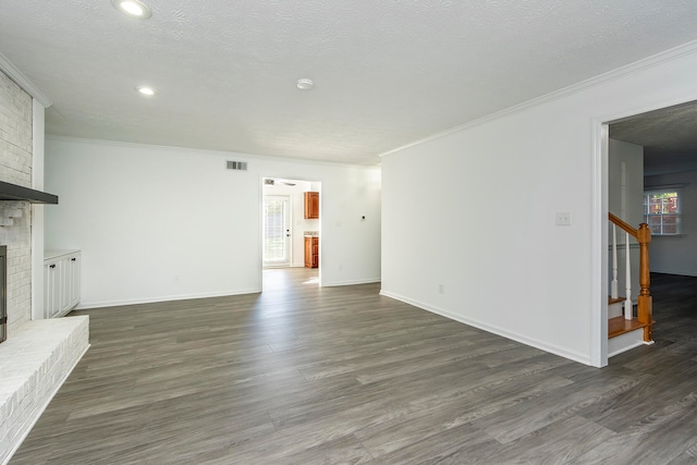 unfurnished living room featuring ornamental molding, a brick fireplace, dark wood-type flooring, and a textured ceiling