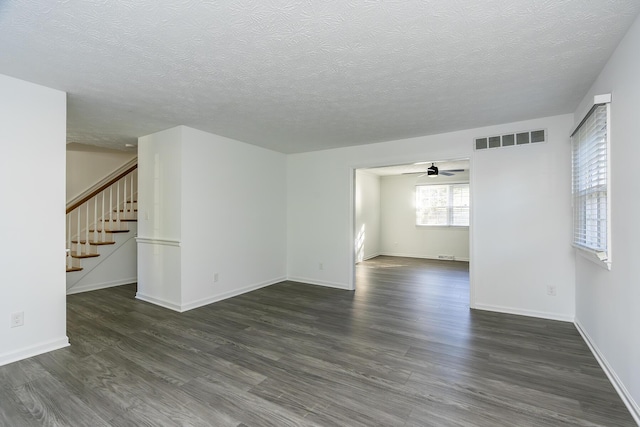 unfurnished living room with a textured ceiling, ceiling fan, visible vents, and dark wood-type flooring