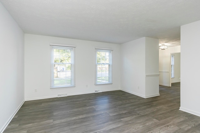 spare room featuring dark hardwood / wood-style flooring and a textured ceiling