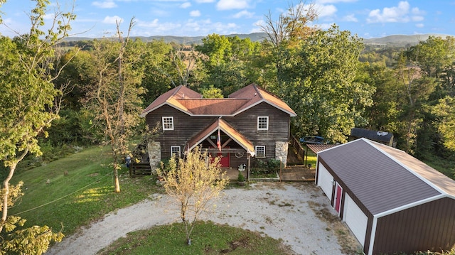 view of front facade featuring a front lawn, a mountain view, an outdoor structure, and a garage