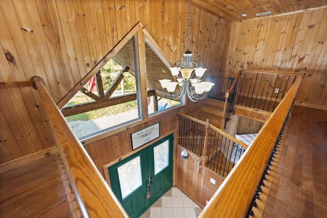 interior space with a notable chandelier, wooden walls, tile patterned flooring, and wood ceiling